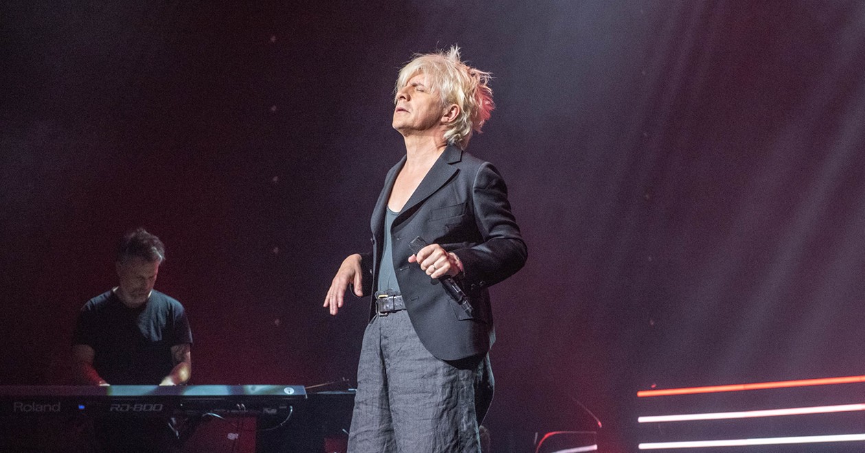 Nicola Sirkis d'Indochine en concert, micro en main, sous les projecteurs.