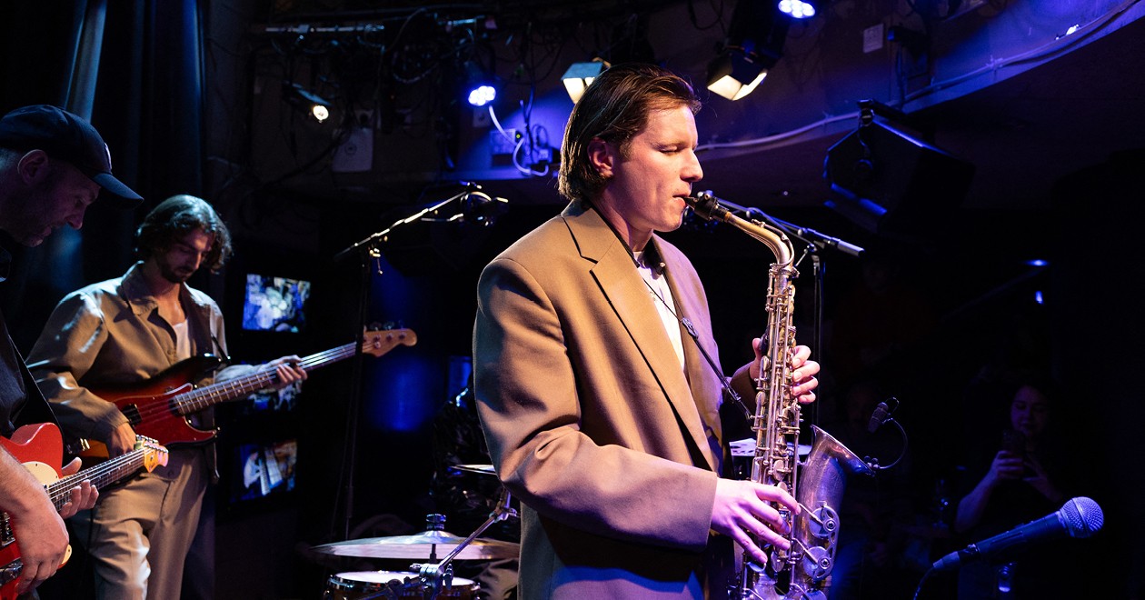 Ferdi en concert, jouant du saxophone sur scène avec ses musiciens.