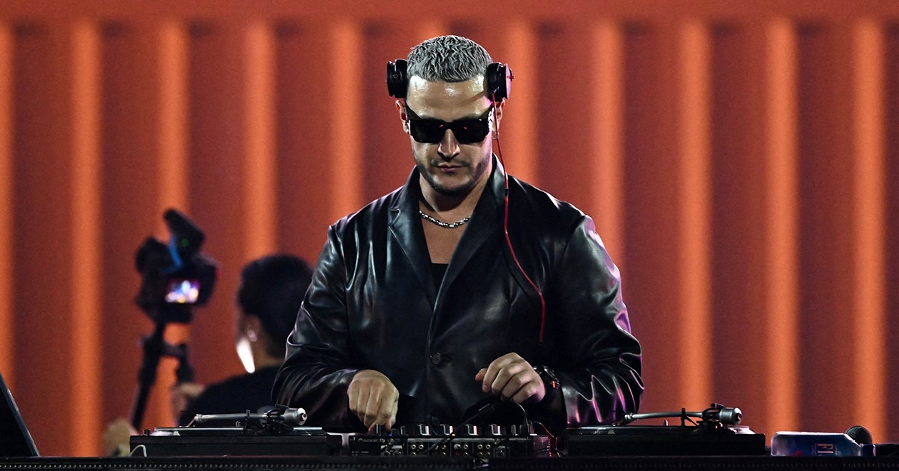 DJ Snake at the decks during a live performance, wearing headphones